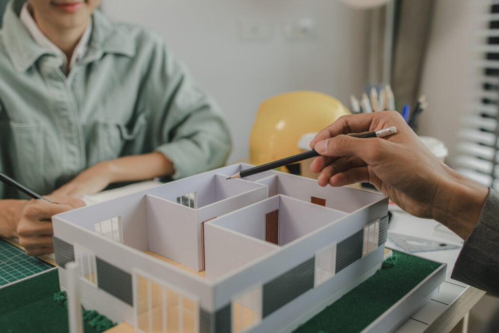 „Zespół architektów tworzących nowoczesny projekt budowy domu drewnianego, który łączy innowacyjne podejście do konstrukcji z naturalnym pięknem drewna. Projekt uwzględnia zarówno aspekty funkcjonalne, jak i estetyczne, tworząc przestronną i zrównoważoną przestrzeń, idealnie wpisującą się w otoczenie.”